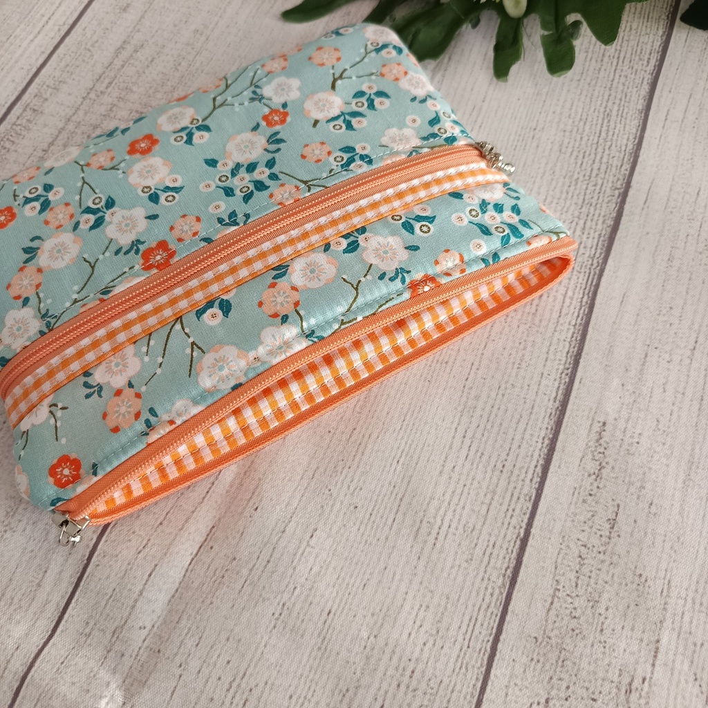 Neceser de tela floral verde con cierre naranja ideal para maquillaje y viaje