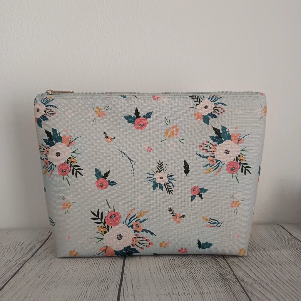 Detalle del tejido impermeable y cremallera resistente del neceser organizador de cosméticos con diseño botánico.