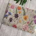 Neceser plano de tela floral con cremallera sobre fondo claro