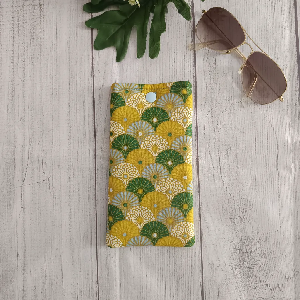 Funda de tela para gafas con estampado de abanicos japoneses en colores verde, amarillo y azul claro.