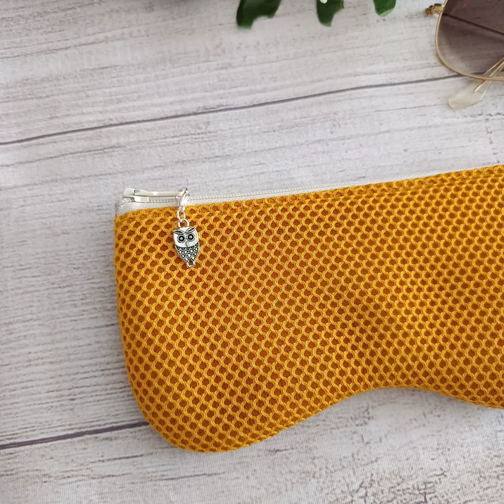 Funda de gafas hecha a mano en tejido mostaza con cremallera sobre fondo claro
