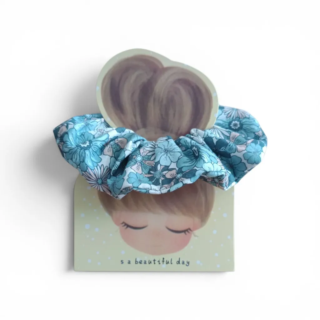 Coletero artesanal hecho a mano con tela floral en tonos azules y rosas sobre fondo blanco