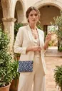 Bolso de tela floral azul con cadena bandolera llevado por mujer