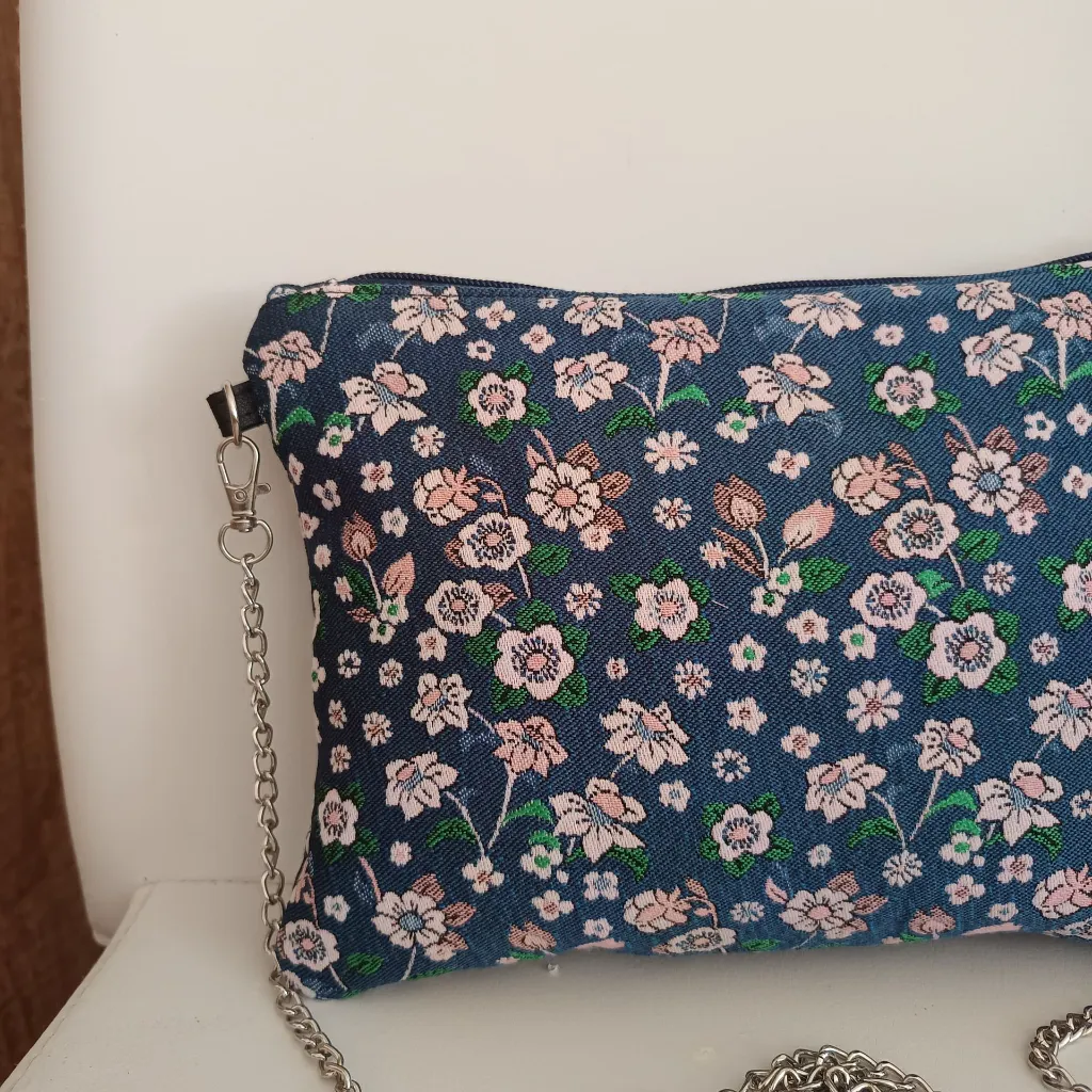 Bolso de tela artesanal con estampado floral y cadena metálica.