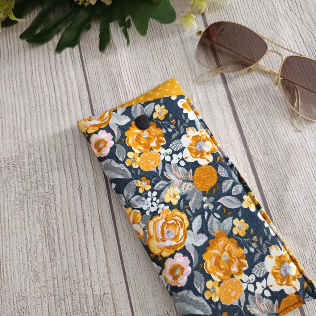 Funda de gafas artesanal de tela con estampado floral en azul navy y flores mostaza dorado, hecha a mano con cierre a presión
