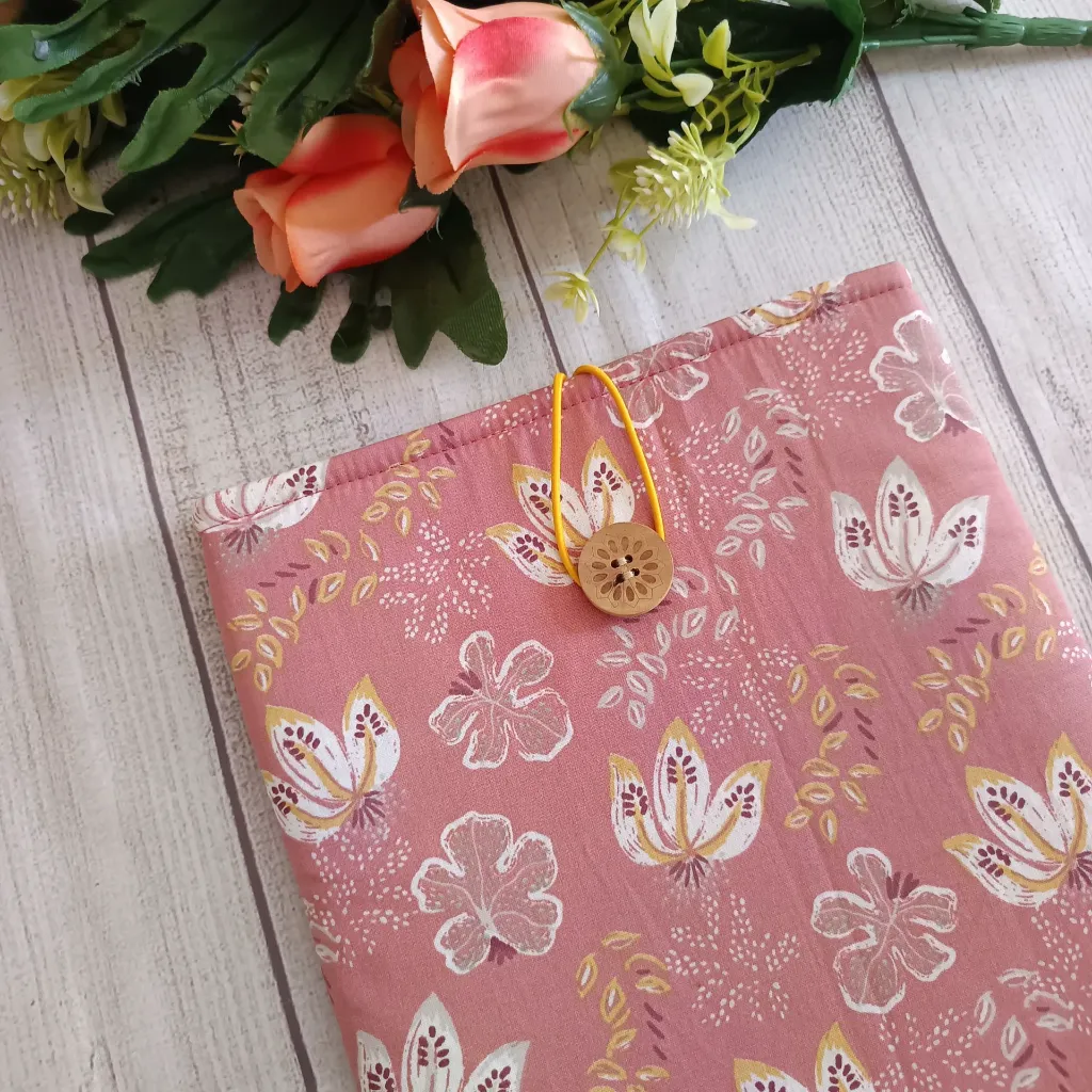 Estuche para libro artesanal de tela rosa con estampado floral y cierre de botón de madera.