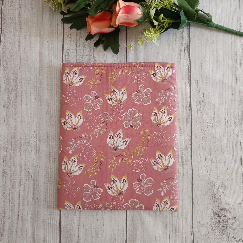 Estuche para libro artesanal con estampado botánico sobre fondo rosa, perfecto para transportar libros.