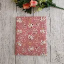 Estuche para libro artesanal con estampado botánico sobre fondo rosa, perfecto para transportar libros.
