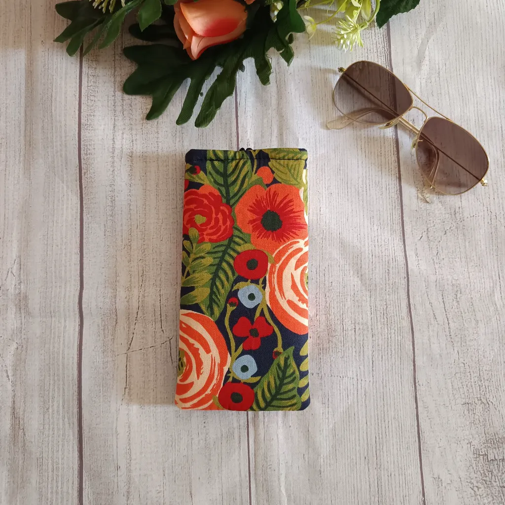 Funda de gafas tela floral junto  a unas gafas de sol