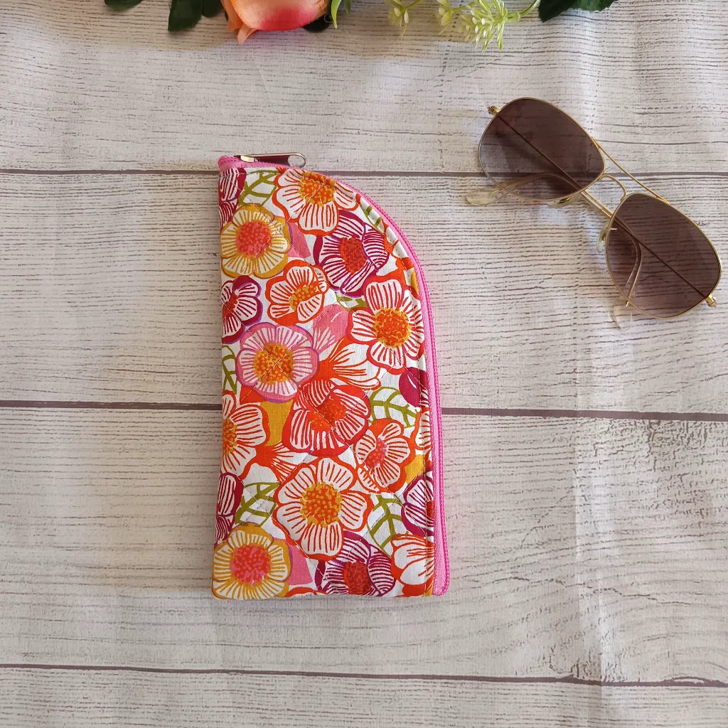 Funda de gafas de tela con cremallera estampado floral en tonos rosas y naranjas hecha a mano.